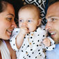 Mutter und Vater liegen mit ihrem Baby auf einer Decke.