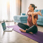 Eine Frau macht Yoga vor dem Notebook.