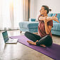 Eine Frau macht Yoga vor dem Notebook.