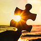 Ein Puzzleteil wird hochgehalten.