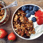 Eine Schale mit Müsli, Joghurt, Erdbeeren und Blaubeeren.