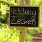 Ein Schild im Wald, auf dem "Achtung Zecken" steht