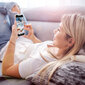 Eine Frau liegt mit ihrem Smartphone auf dem Sofa.