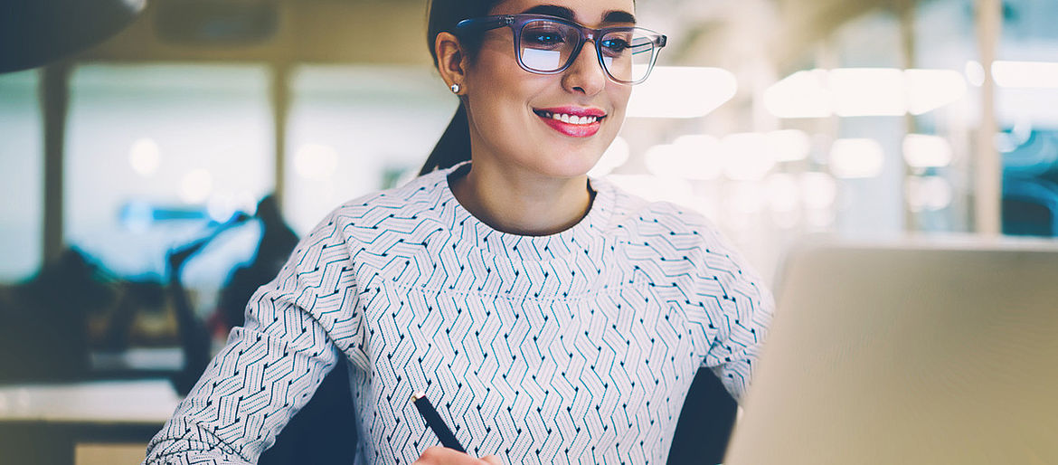 Eine Frau schaut auf einen Computer. Eine Frau arbeitet am Computer.