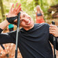 Ein Mann steht im Wald mit Nordic Walking Stöcken.